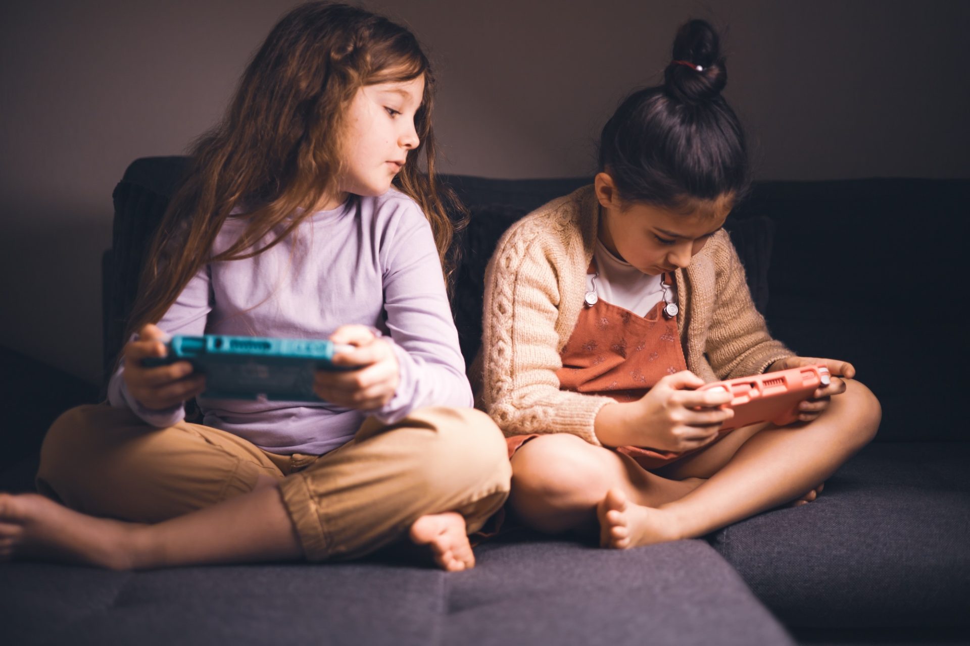 Deux copines Preteen jouent activement à des jeux vidéo sur la console, assis confortablement sur le canapé à la maison.