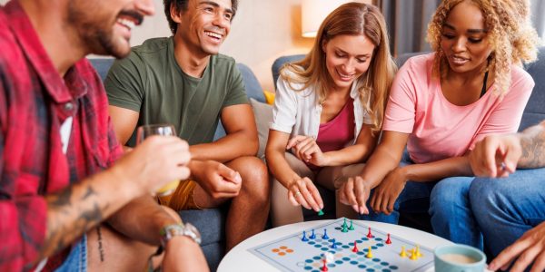 Découvrez des critiques captivantes sur les jeux de société modernes et classiques Groupe de jeunes amis joyeux qui s'amusent à jouer au jeu de société Ludo tout en passant du temps ensemble à la maison
