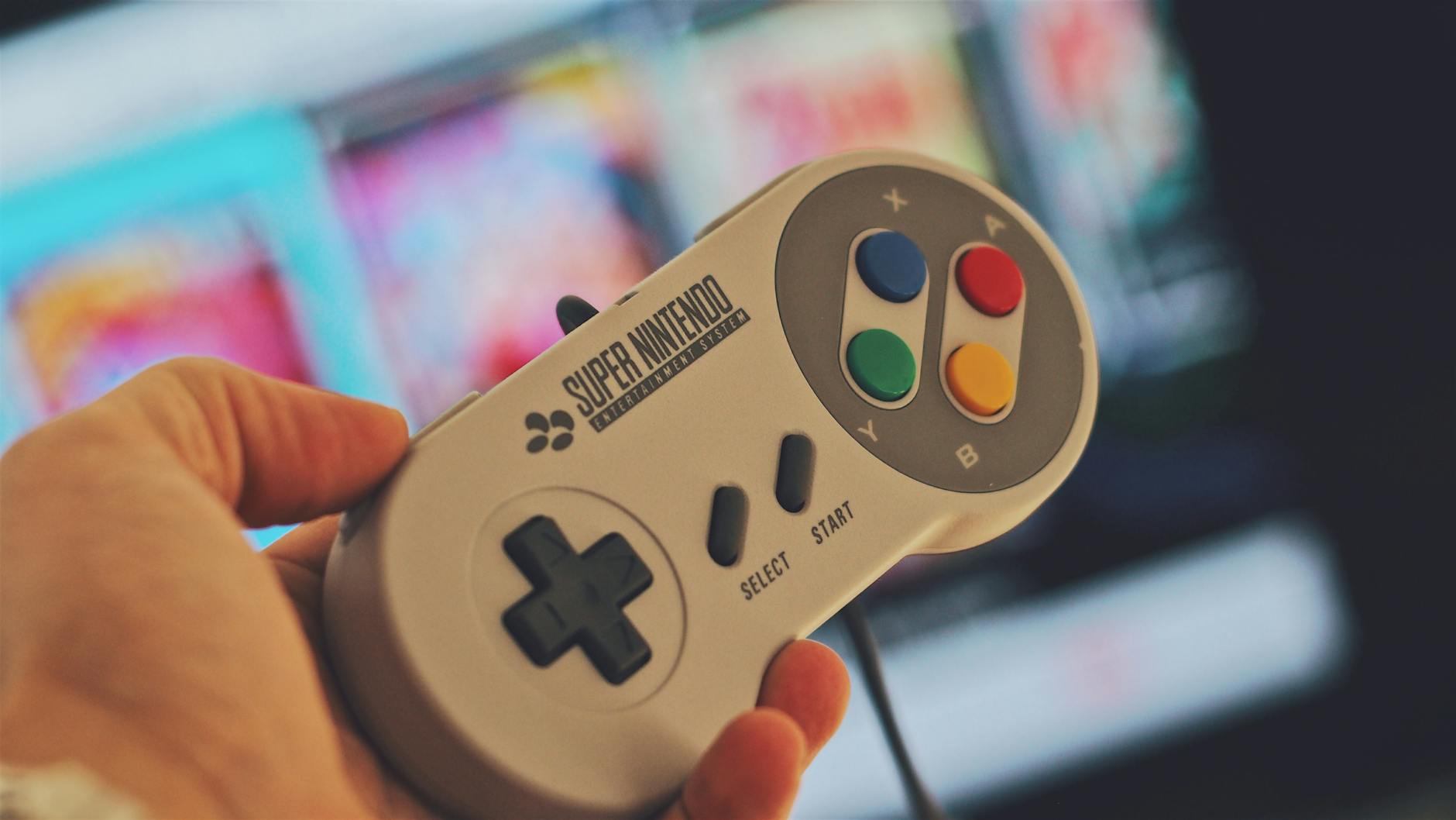 Hand tenant un contrôleur de jeu Super Nintendo classique à l'intérieur avec un écran flou en arrière-plan.