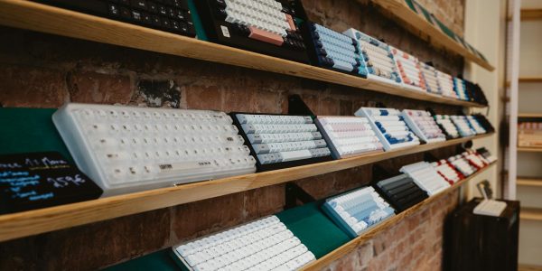 Découvrez comment choisir le produit idéal pour vos besoins et votre budget Une variété de claviers mécaniques soigneusement exposés sur une étagère dans un intérieur de magasin aux murs de briques.