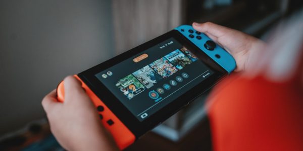 Prix de la nintendo switch 1 au japon : histoire, comparaisons et conseils personne tenant une Nintendo Switch noire et orange