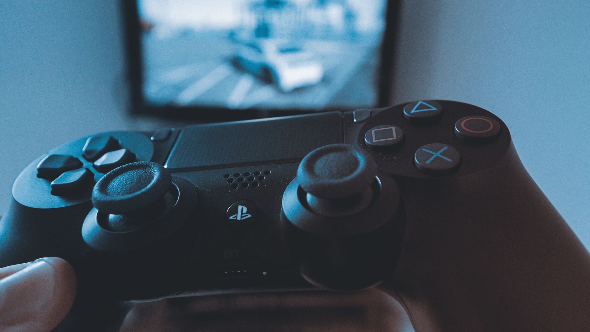 Une main tenant une manette de jeu sans fil devant un écran flou, capturant l'expérience de jeu.