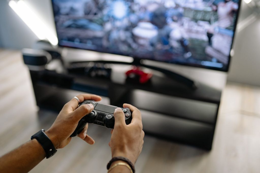 Gros plan des mains tenant une manette de jeu tout en jouant à des jeux vidéo à l'intérieur.
